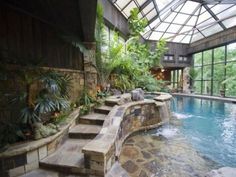 an indoor swimming pool with steps leading up to it and lots of greenery in the background