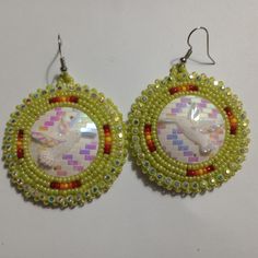 the earrings are decorated with colorful beads and an image of a unicorn on it's face