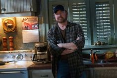 a man standing in a kitchen with his arms crossed