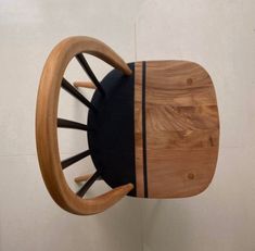 a wooden rocking chair with black cushions and wood spokes on the back, against a white wall