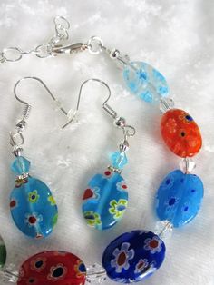 This multi-colored adjustable millefiori bracelet set is made with 14mm flat ovals and includes blue, red, orange, and green multi-colored beads. The bracelet adjusts from 7 inches to 8 inches. The earrings dangle 1 inch from the loops of the silver plated ear wires. This set will be slipped into an organza bag and shipped in a bubble mailer. Adjustable Multicolor Czech Glass Jewelry, Colorful Oval Beaded Jewelry Gift, Adjustable Multicolor Oval Bracelets, Adjustable Oval Multicolor Bracelets, Multicolor Czech Glass Jewelry With Oval Beads, Millefiori Bracelet, Oval Earrings, Orange And Green, Oval Earring