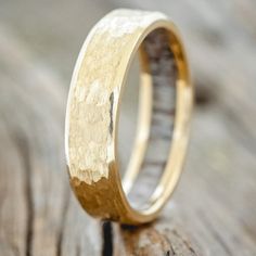 a gold wedding ring sitting on top of a wooden table