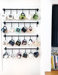 there are many cups hanging on the wall and mugs attached to the rack in this room