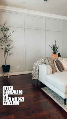 a white couch sitting on top of a wooden floor next to a potted plant