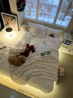 a bed with white blankets and pillows on top of it in front of a window