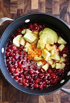 apples and cranberries are being cooked in a pot