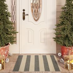 two potted christmas trees sitting on the front step of a house, next to a door