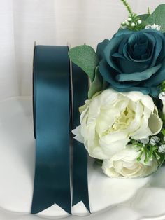 a bouquet of flowers on a plate with a blue ribbon tied around the center and green leaves