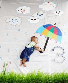 a baby laying on top of a blanket holding an umbrella