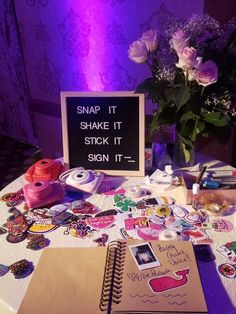 a table topped with lots of stickers next to a vase filled with flowers and writing