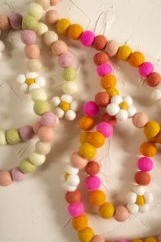 multicolored pom - poms are arranged on a white surface, with one bead in the middle