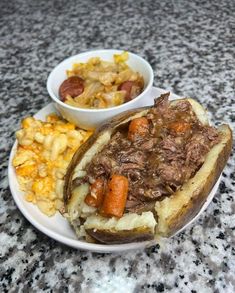 a white plate topped with food next to a bowl of macaroni and cheese