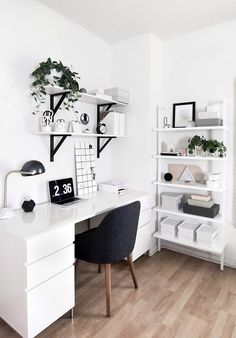 a white desk topped with a computer monitor next to a book shelf filled with books