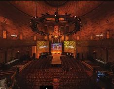 an empty auditorium with rows of seats in front of large screen televisions and chandeliers