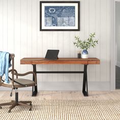 a desk with a laptop on it and a chair next to it in front of a white wall