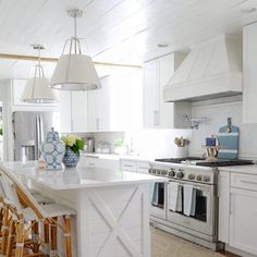 a kitchen with white cabinets and an island in the middle, surrounded by stools