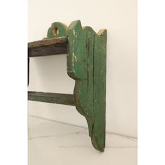 an old green wooden shelf on a white wall