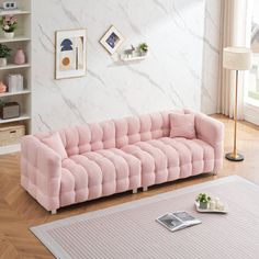 a living room with a pink couch and coffee table on the floor in front of a white wall