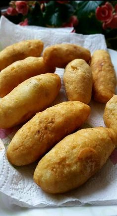 some fried food is sitting on a paper towel next to a potted plant with flowers in the background