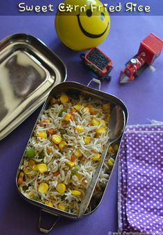 a metal container filled with rice and vegetables next to a toy train on a table