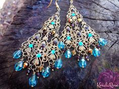 These Antique Brass Filigree Moroccan Boho Chandelier Earrings are made with hand-antiqued brass filigrees tiered to form a beautiful classic chandelier shape. Peacock Teal, Garnet Red and Metallic Gold crystal beads hang on each tier. Swarovski rhinestones add a touch of sparkle! Available Bohemian Jeweled Chandelier Earrings As Gift, Bohemian Teardrop Chandelier Earrings For Celebration, Bohemian Festive Chandelier Earrings For Celebration, Festive Bohemian Chandelier Earrings For Celebration, Bohemian Jeweled Dangle Chandelier Earrings, Festive Bohemian Chandelier Earrings With Dangling Beads, Festive Bohemian Jeweled Earrings, Bohemian Chandelier Earrings For Weddings And Festivals, Bohemian Jeweled Gold Earrings