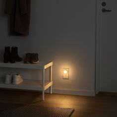 a light that is on in the middle of a room next to a shelf with shoes