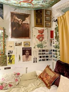 there is a bed with many pictures on the wall and pillows in front of it