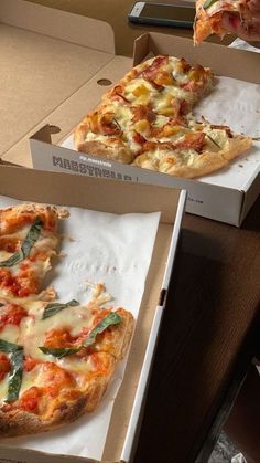 two pizzas in boxes one with cheese and the other with spinach on it