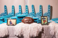 a table topped with a football next to blue chairs and pictures on the side of it