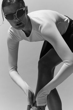 a woman in white shirt and black shorts holding her hands on her hip while wearing sunglasses