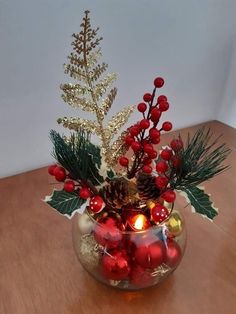 a glass vase filled with christmas decorations on top of a wooden table