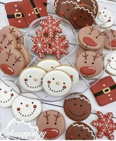 decorated cookies and pastries are arranged on a glass platter with santa's helpers