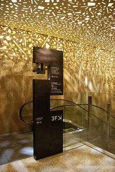 the inside of an art gallery with gold and black artwork on the walls, glass railings and flooring