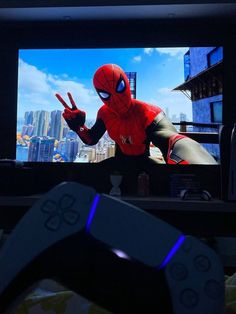 a video game controller sitting in front of a television with the spider man on it