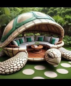 a turtle shaped couch sitting on top of a lush green field next to a wooden table