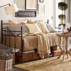 a bed with lots of pillows on top of it next to a table and chair