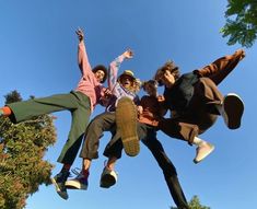 three young men jumping in the air with their feet on each other's shoulders