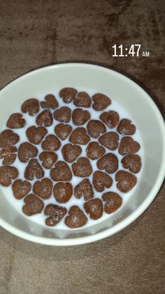 a white bowl filled with milk and brown dog treats on top of a wooden table