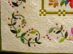 a quilted wall hanging with flowers and leaves on it's border, in the shape of a frame