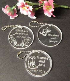 three personalized glass key chains with flowers in the background on a black table top