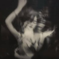 black and white photograph of a woman dancing in the dark with her arms behind her head