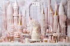 a table topped with lots of cakes and cupcakes next to a castle wall