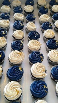 cupcakes with white and blue frosting are lined up on a baking sheet