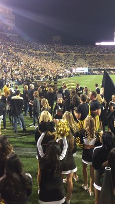 a group of cheerleaders huddle together on the field at a football game