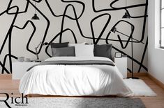 a white bed sitting in a bedroom next to a black and white painting on the wall