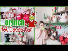 a woman standing in front of a kitchen counter with christmas decorations on the wall and shelves