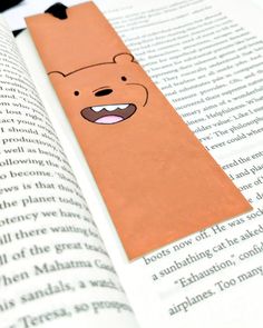 a bookmark with a bear on it sitting next to an open page of a book