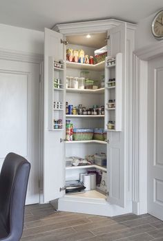 an open pantry door in the corner of a room with a clock on the wall