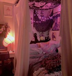 a canopy bed with purple lights hanging from it's sides and pillows on the floor