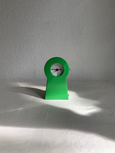 a green clock sitting on top of a white table